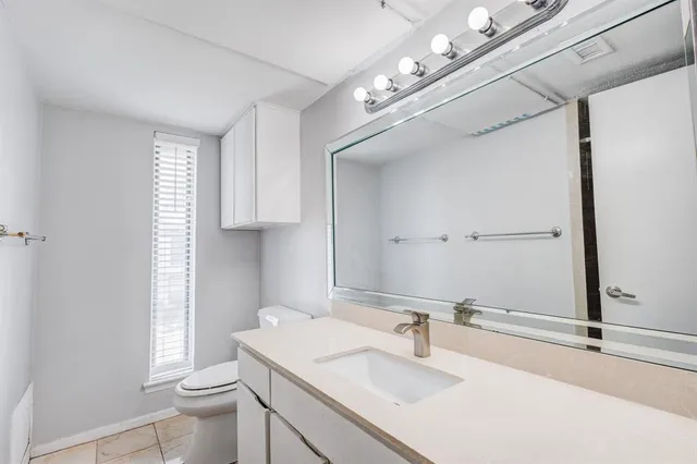 a bathroom with a sink vanity granite toilet and a mirror