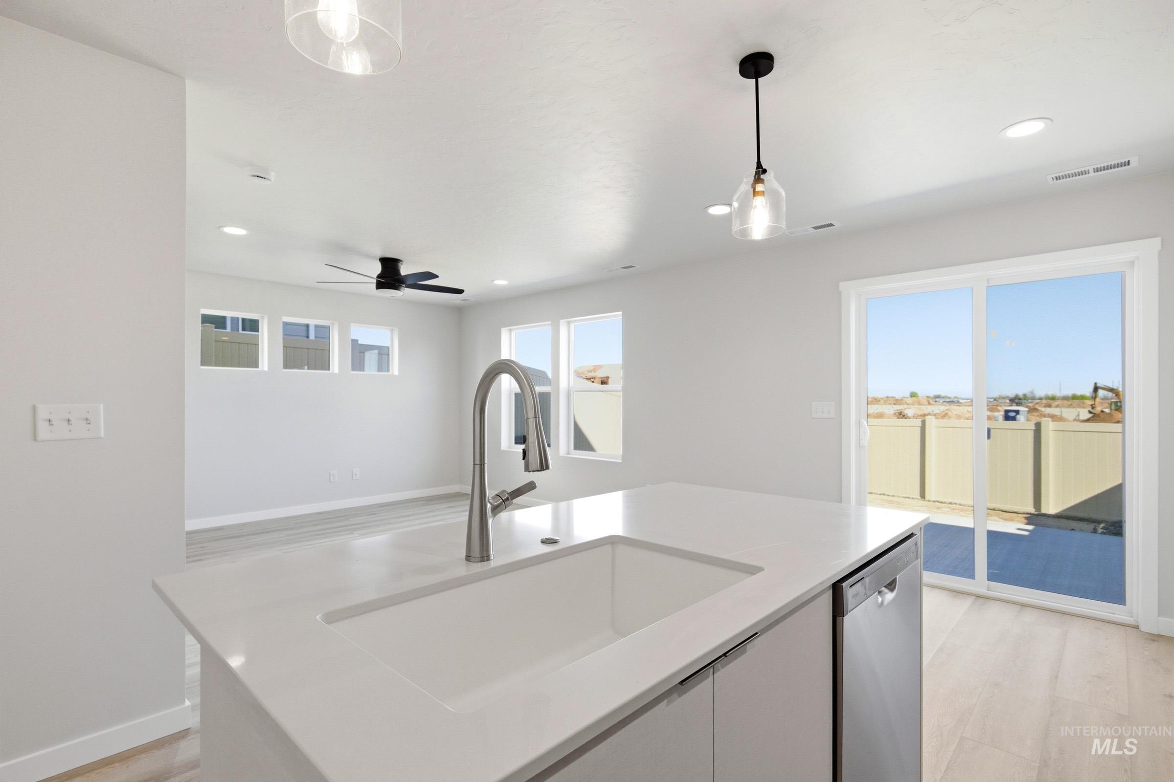 10812 Rutland Street Caldwell, ID 83605 - Photo 8 of 21 Spacious kitchen island featuring an integrated sink with a gooseneck faucet, light-toned countertop, and stainless steel dishwasher