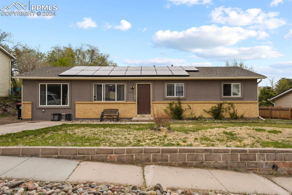 Ranch-style home with solar panels and a front yard