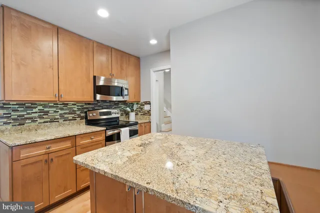 a kitchen with stainless steel appliances granite countertop a stove a sink and a microwave