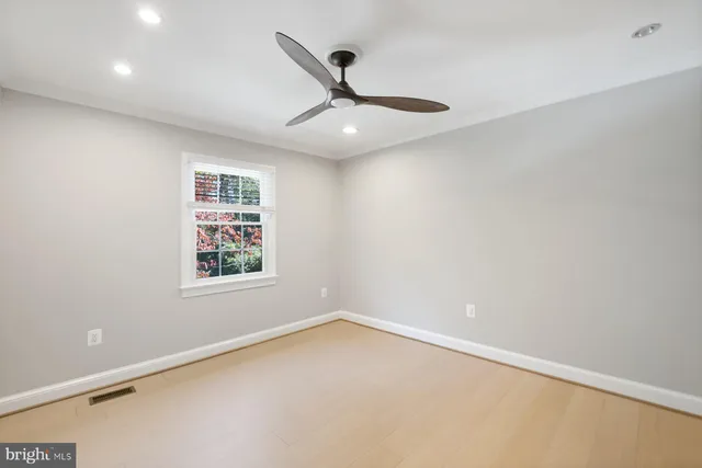 an empty room with a ceiling fan and window