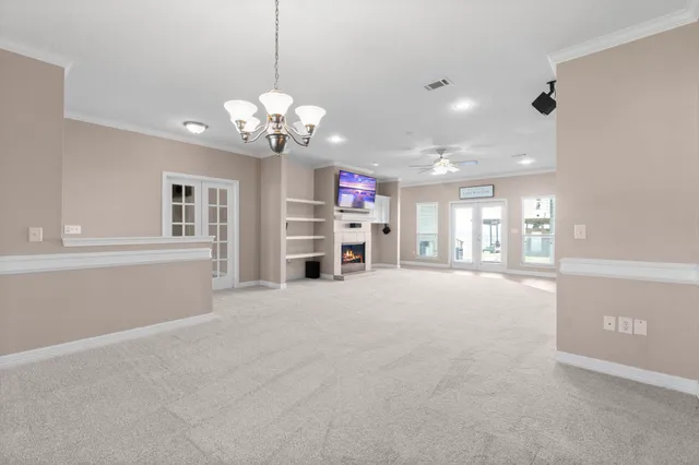 a view of a livingroom with a chandelier fan and windows