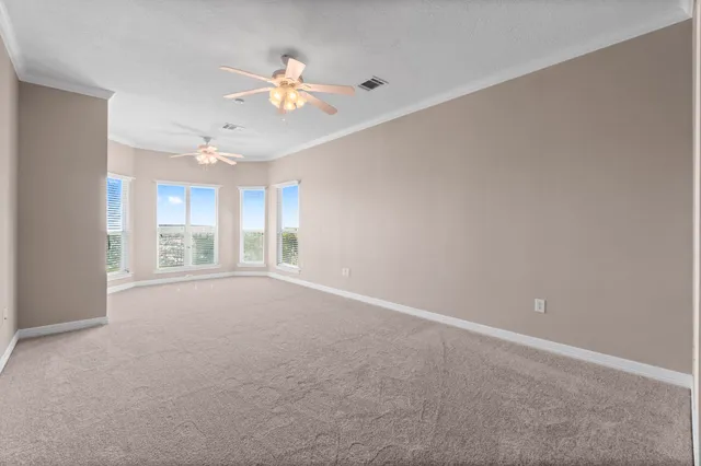 an empty room with windows and chandelier fan