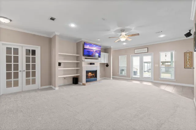 a view of a livingroom with a flat screen tv ceiling fan and windows