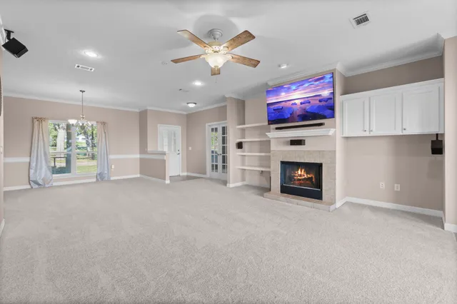 a view of a livingroom with a ceiling fan a fireplace and a window