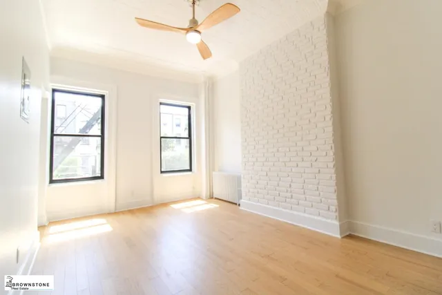 an empty room with wooden floor fan and windows
