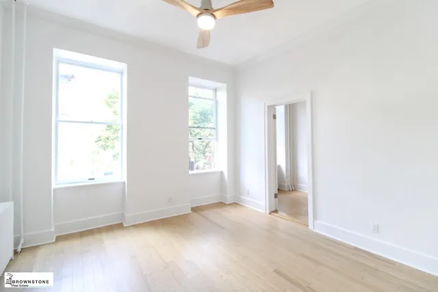 an empty room with a window and a ceiling fan