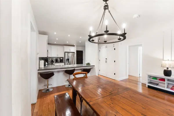 a living room with stainless steel appliances kitchen island granite countertop furniture and a chandelier