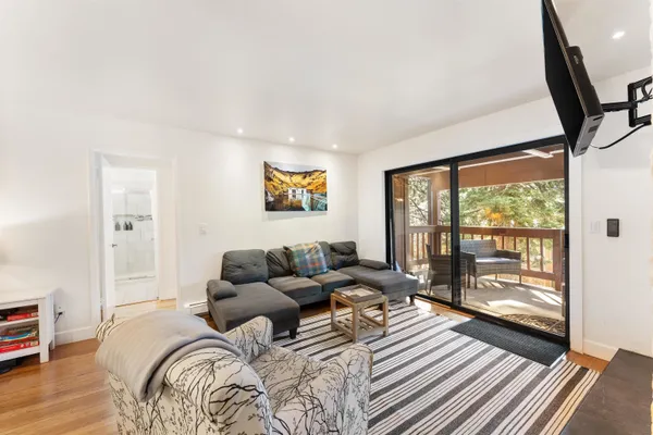 a bedroom with a bed couch and a large window with wooden floor