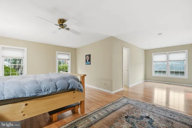 a view of empty room with wooden floor and fan