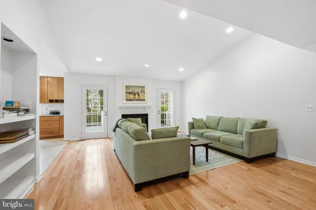 a living room with furniture wooden floor and a kitchen view