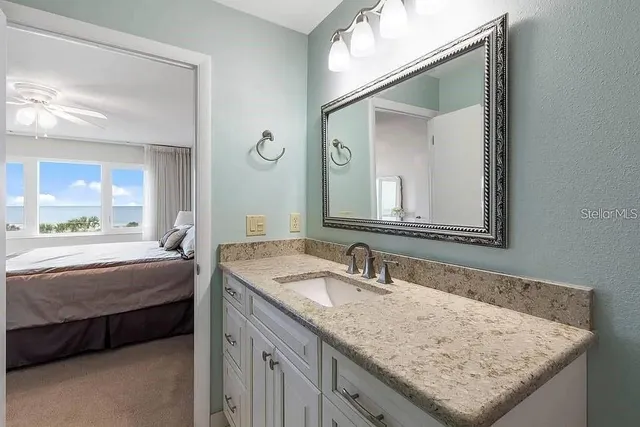 a en suite bathroom with a granite countertop sink and a mirror