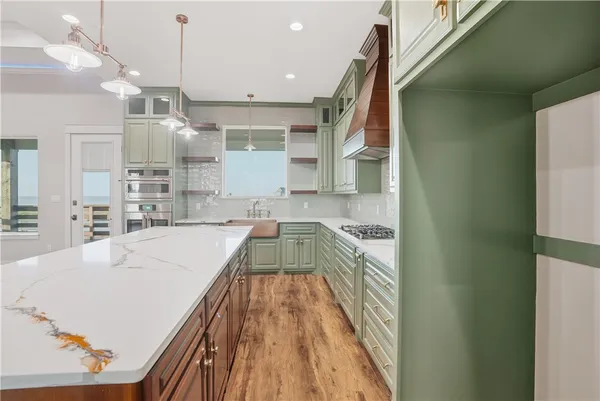 a kitchen with kitchen island a counter top space a sink stainless steel appliances and cabinets