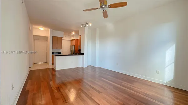 an empty room with wooden floor fan and windows