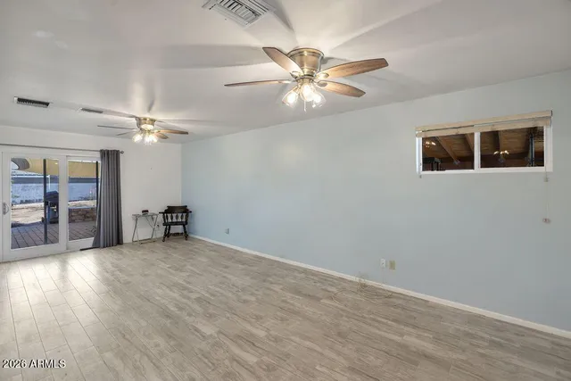 an empty room with wooden floor and chandelier