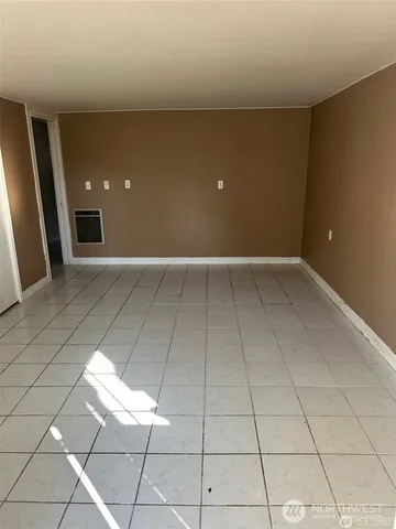 a view of a refrigerator in kitchen and an empty room