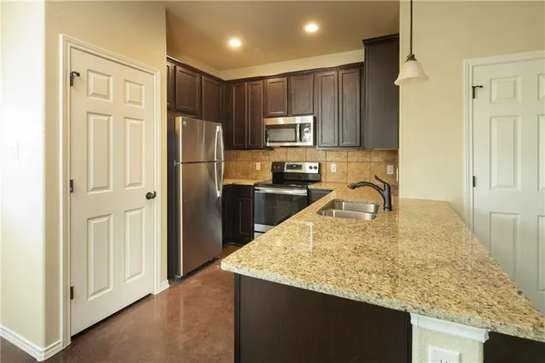a kitchen with kitchen island granite countertop a refrigerator a stove and a sink