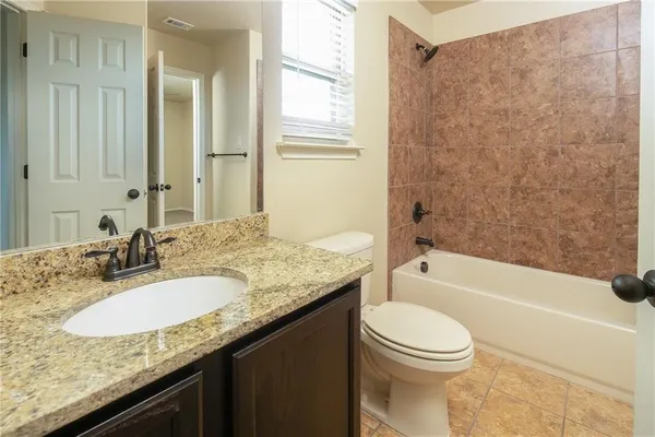 a bathroom with a granite countertop sink a toilet and bathtub