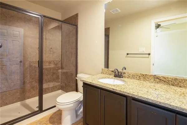 a bathroom with a granite countertop sink toilet and shower