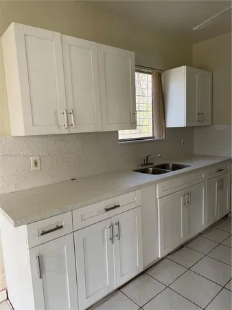 a kitchen with white cabinets white appliances and a sink