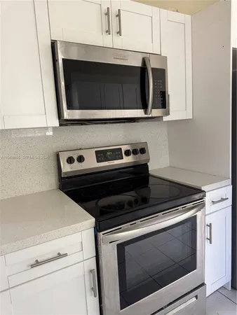 a kitchen with granite countertop white cabinets and stainless steel appliances