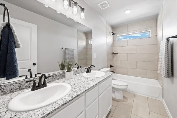 a bathroom with a granite countertop sink a toilet a mirror a bathtub and shower