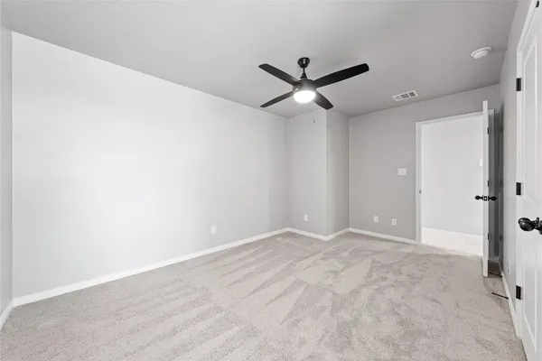 an empty room with closet and a ceiling fan