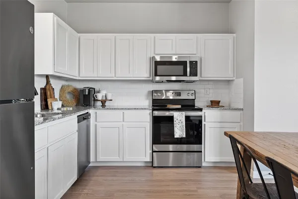 a kitchen with white cabinets stainless steel appliances and wooden floor