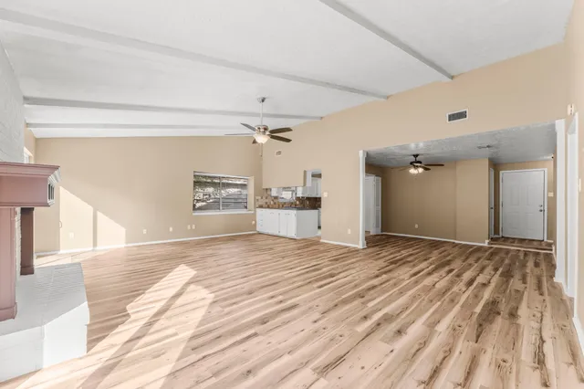 a view of empty room with wooden floor and fireplace