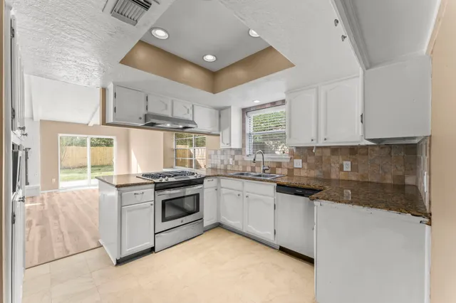 an empty room with windows and chandelier fan