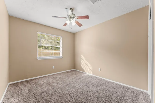 an empty room with a ceiling fan and a window