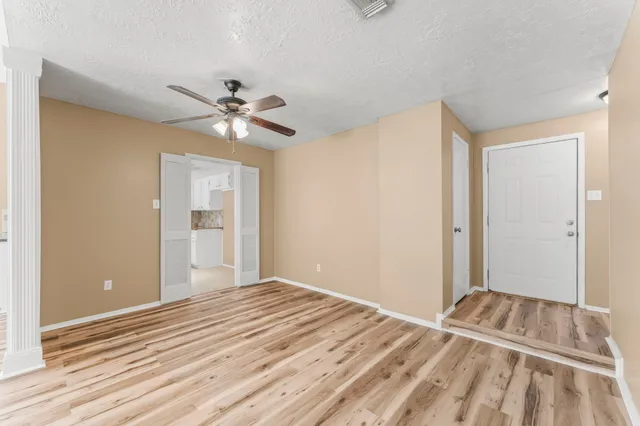a view of an empty room with a window and wooden floor