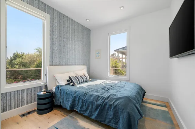a view of a hallway with wooden floor and a bathroom