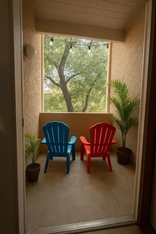 a balcony with couple of chairs and a potted plant