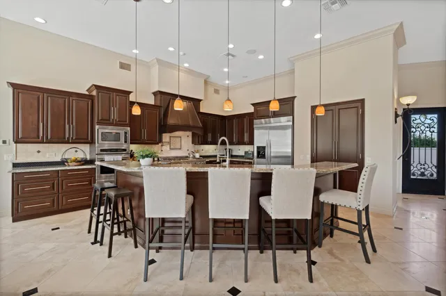 a kitchen with stainless steel appliances kitchen island granite countertop a stove a sink a refrigerator and a cabinets