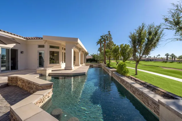 a view of a house with pool and chairs