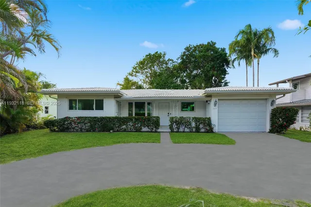 a front view of a house with a garden and trees