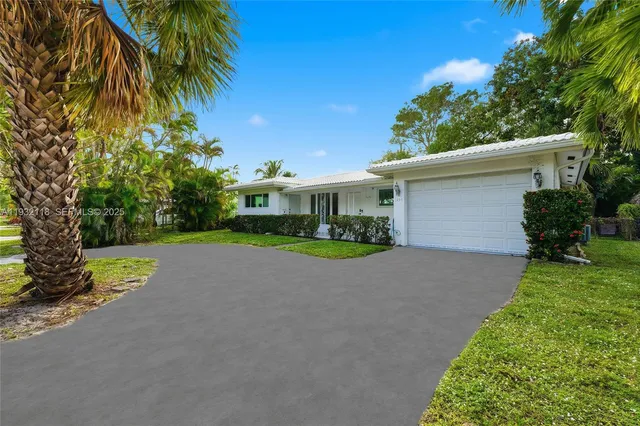 a view of a house with a yard and palm trees