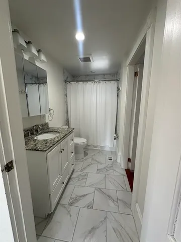 a spacious bathroom with a granite countertop sink a mirror and a shower