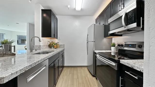 a kitchen with stainless steel appliances granite countertop a sink stove and refrigerator