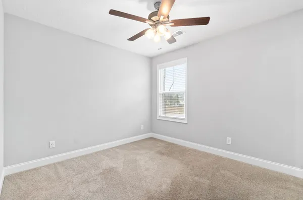 an empty room with windows and fan