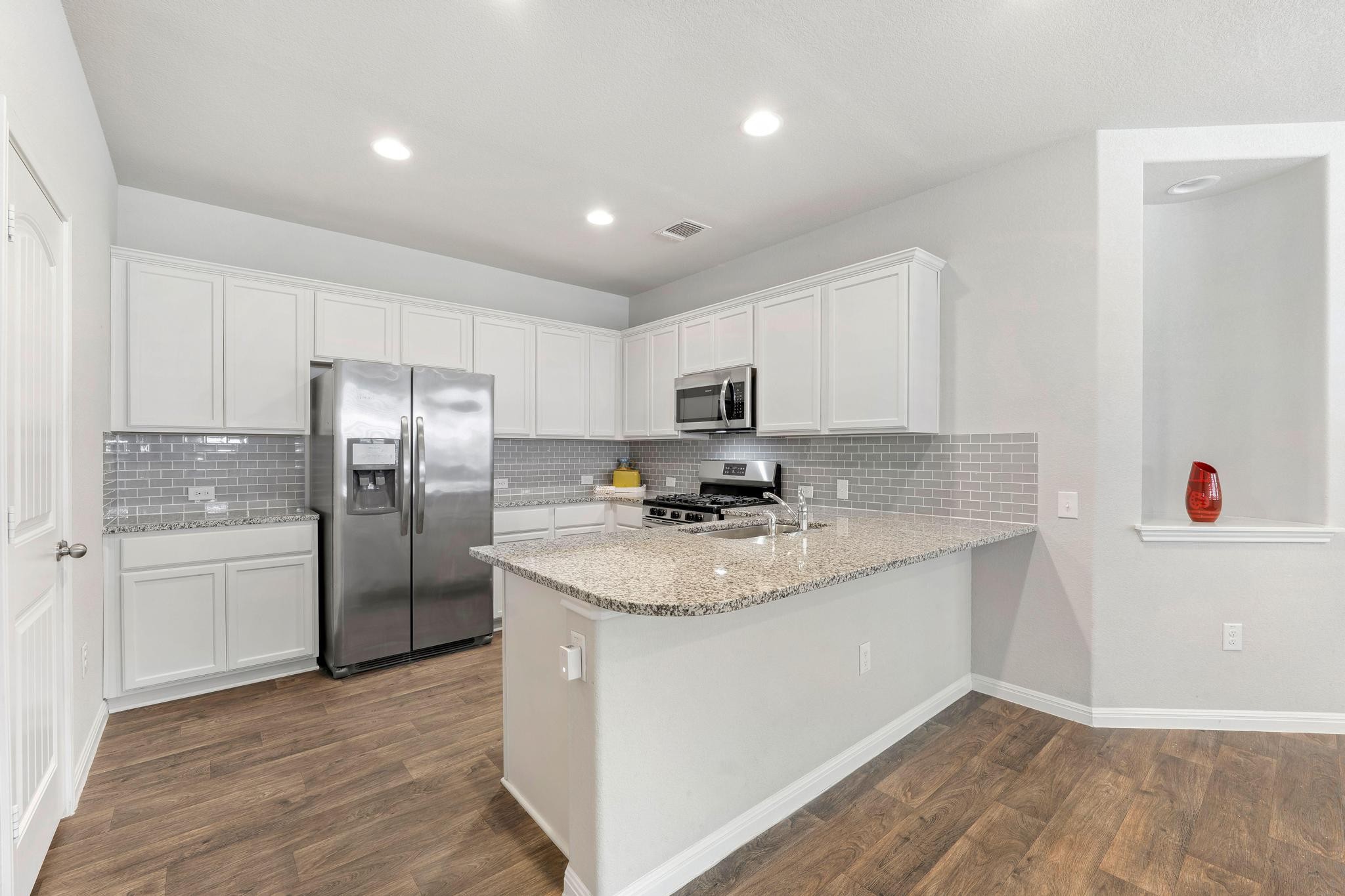 14409 Frankel Loop, Unit 33A Pflugerville, TX 78660 - Photo 11 of 29 Kitchen featuring white cabinetry, stainless steel appliances, light stone counters, a peninsula, and dark wood finished floors