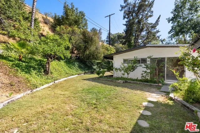 a view of a house with backyard and trees