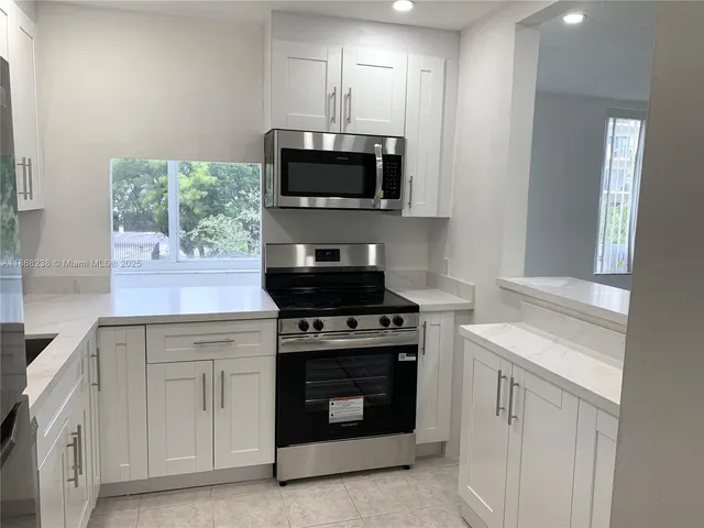 a kitchen with white cabinets and stainless steel appliances