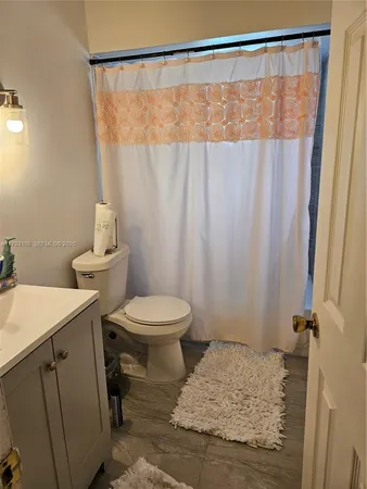 a bathroom with a sink a toilet and shower curtain