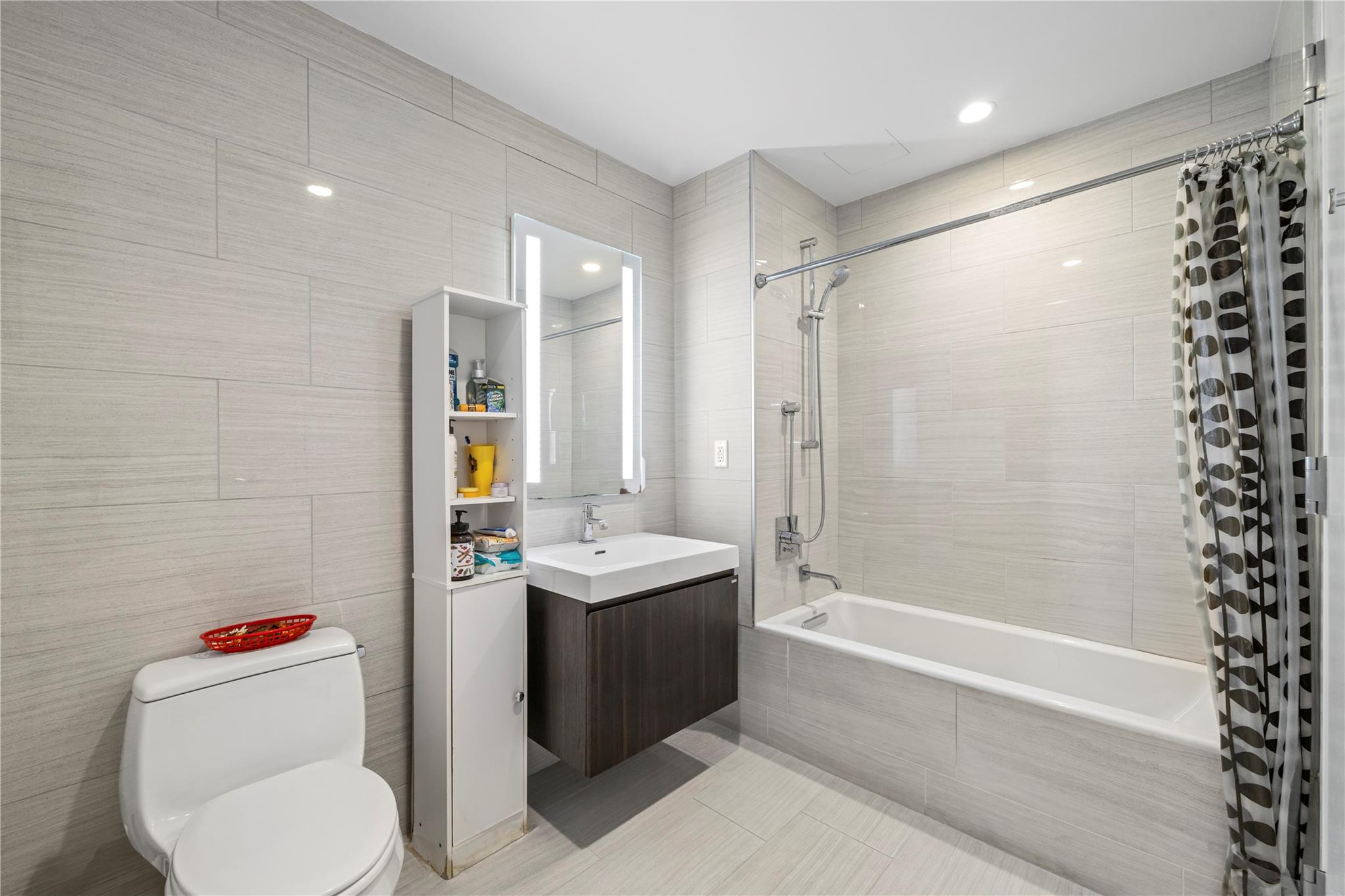 131-05 40 Road, Unit 11M Queens, NY 11354 - Photo 22 of 24 Full bathroom with tile walls, tiled shower / bath combo, vanity, recessed lighting, and tile patterned flooring