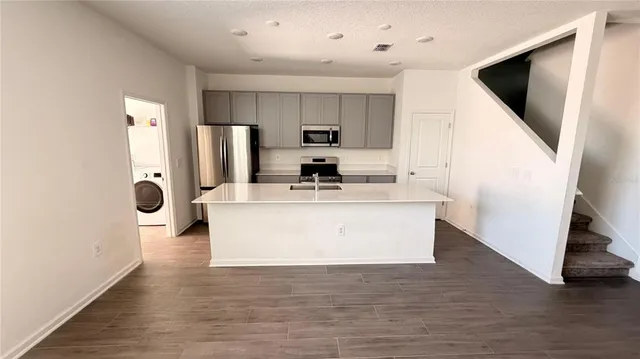 a view of kitchen with stainless steel appliances granite countertop a white stove top oven a refrigerator and a white cabinets