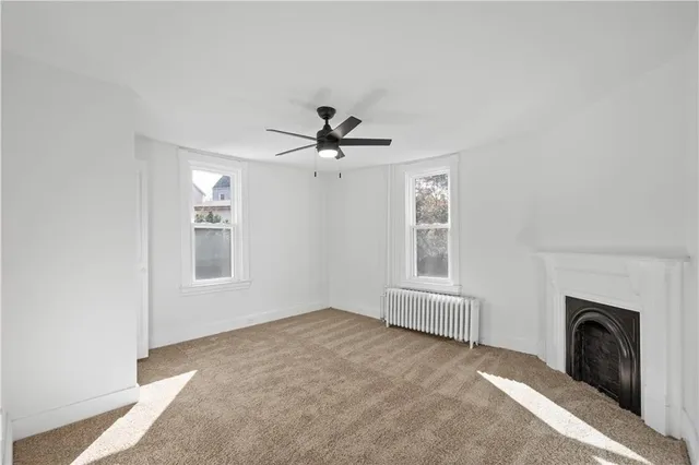 an empty room with windows and fireplace