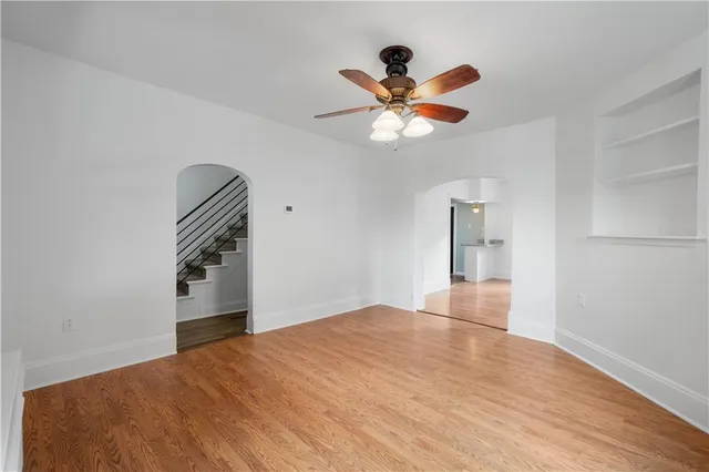 a view of empty room with wooden floor and ceiling fan
