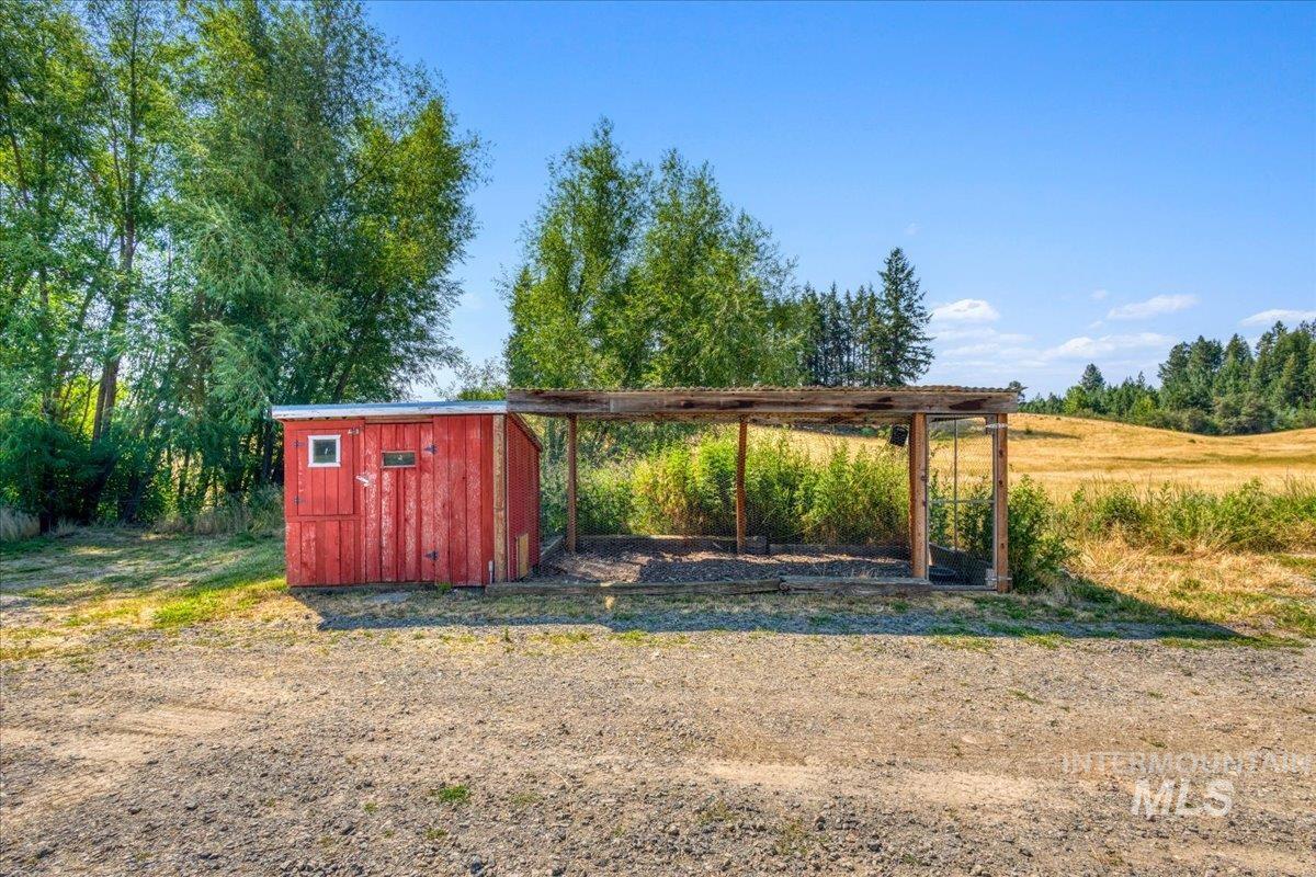 1071 Reynolds Road Princeton, ID 83857 - Photo 29 of 43 Red wooden shed with white trim window, corrugated metal roof, and an attached open-air structure featuring a wood frame